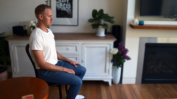 henkilö istuu tuolilla kotona ja meditoi